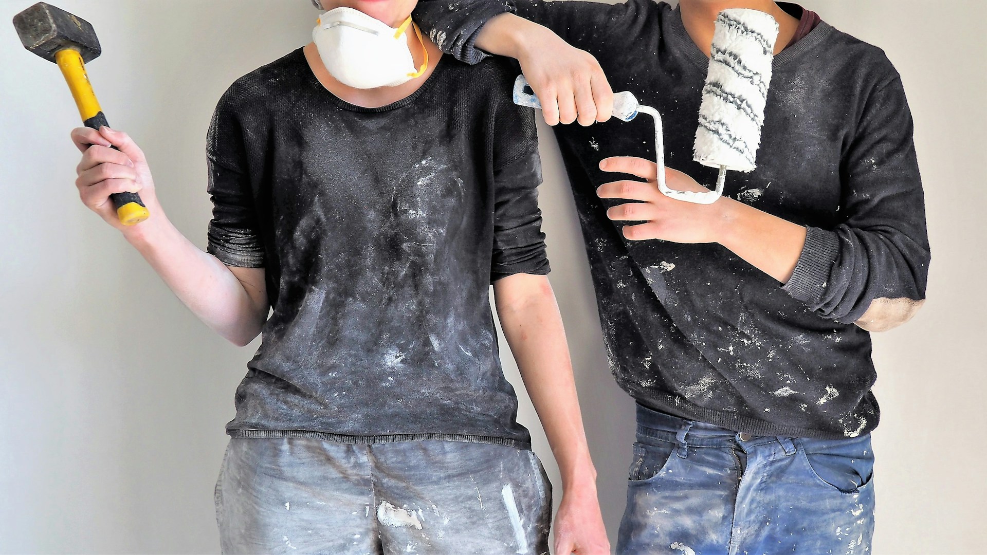 Two professionals covered in dust and paint stand side by side